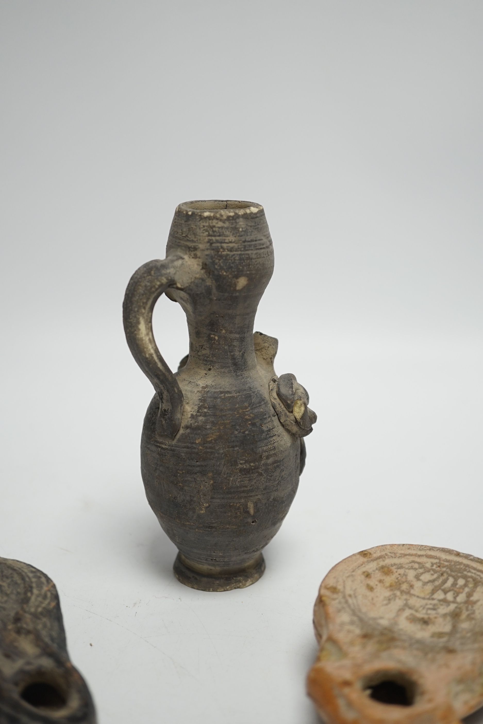Two Roman oil lamps and an early ewer, tallest 14.5cm
